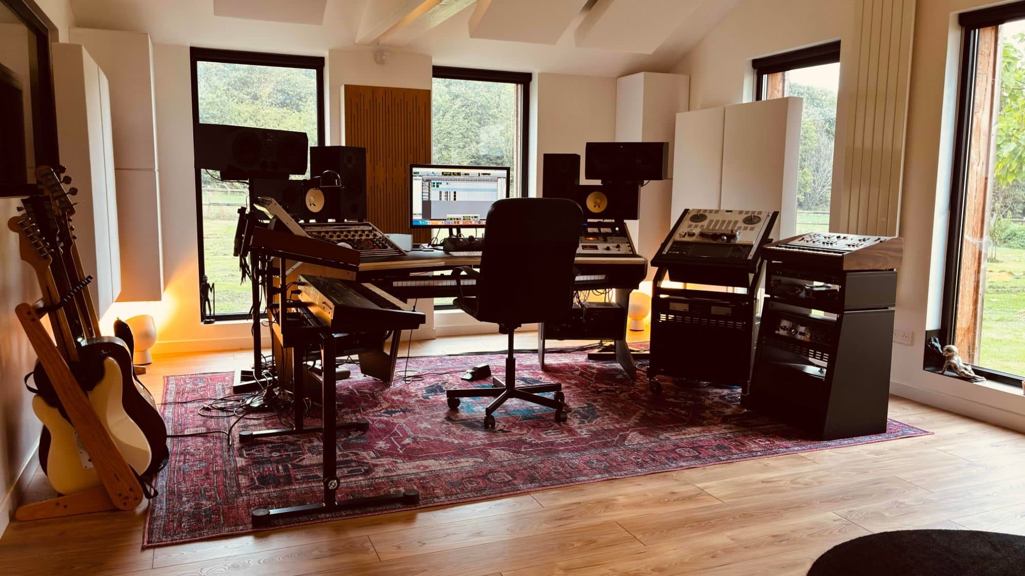 La régie de La Casa Studio : bureau d'enregistrement, enceintes de monitoring, magnétophone à bandes et claviers face aux baies vitrées ouvertes sur la campagne